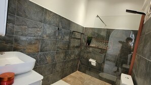Ein modernes Badezimmer mit einem weißen Waschbecken, einer Toilette und einer Duschkabine.