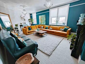 Een woonkamer met een modulaire bank, een salontafel en een kroonluchter.