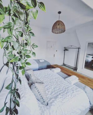A bedroom with a bed, a hanging light fixture, a door, and a window.
