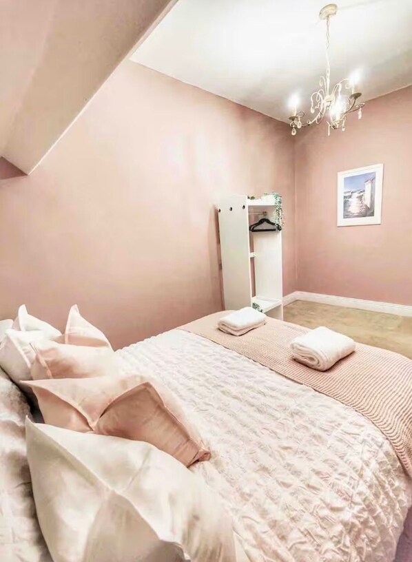 A bedroom with a bed, a bedside table, a mirror, and a picture on the wall.