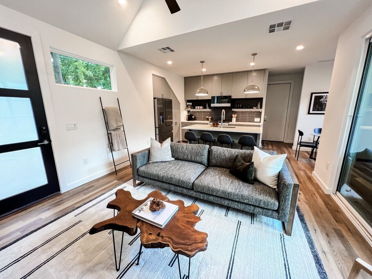 A modern living room with a sofa, coffee table, and a dining area with chairs.