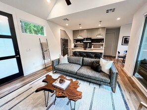 A modern living room with a sofa, coffee table, and a dining area with chairs.