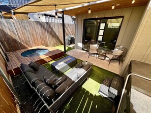 A backyard with a hot tub, a wooden deck, a sofa, and a dining area with chairs. - Luxury Downtown Home w/ Hot Tub Near Lake in Holly (Austin)