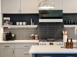 A modern kitchen with a coffee maker, a kettle, a stove, and a range hood. - Luxury Downtown Home w/ Hot Tub Near Lake in Holly (Austin)