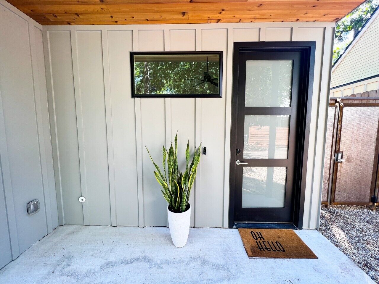 A front door with a doormat, a potted plant, and a framed picture on the wall.