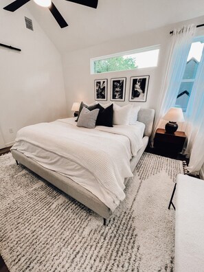 A bedroom with a bed, a nightstand, a window with curtains, and wall art. - Luxury Downtown Home w/ Hot Tub Near Lake in Holly (Austin)