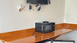 Pieni, mutta toimiva keittiönurkkaus, jossa on mikroaaltouuni, pieni jääkaappi ja seinälle asennettu taulutelevisio.