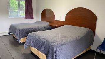 Una habitación con dos camas, una mesita y una ventana con cortinas.