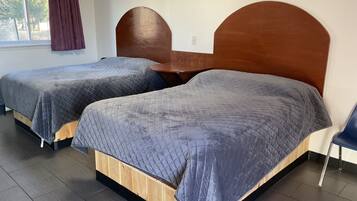 Una habitación con dos camas, cada una con cabecero de madera y ropa de cama gris.