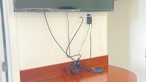 Seinälle asennettu litteä näyttöinen televisio, jonka yläpuolella on puinen työtaso.