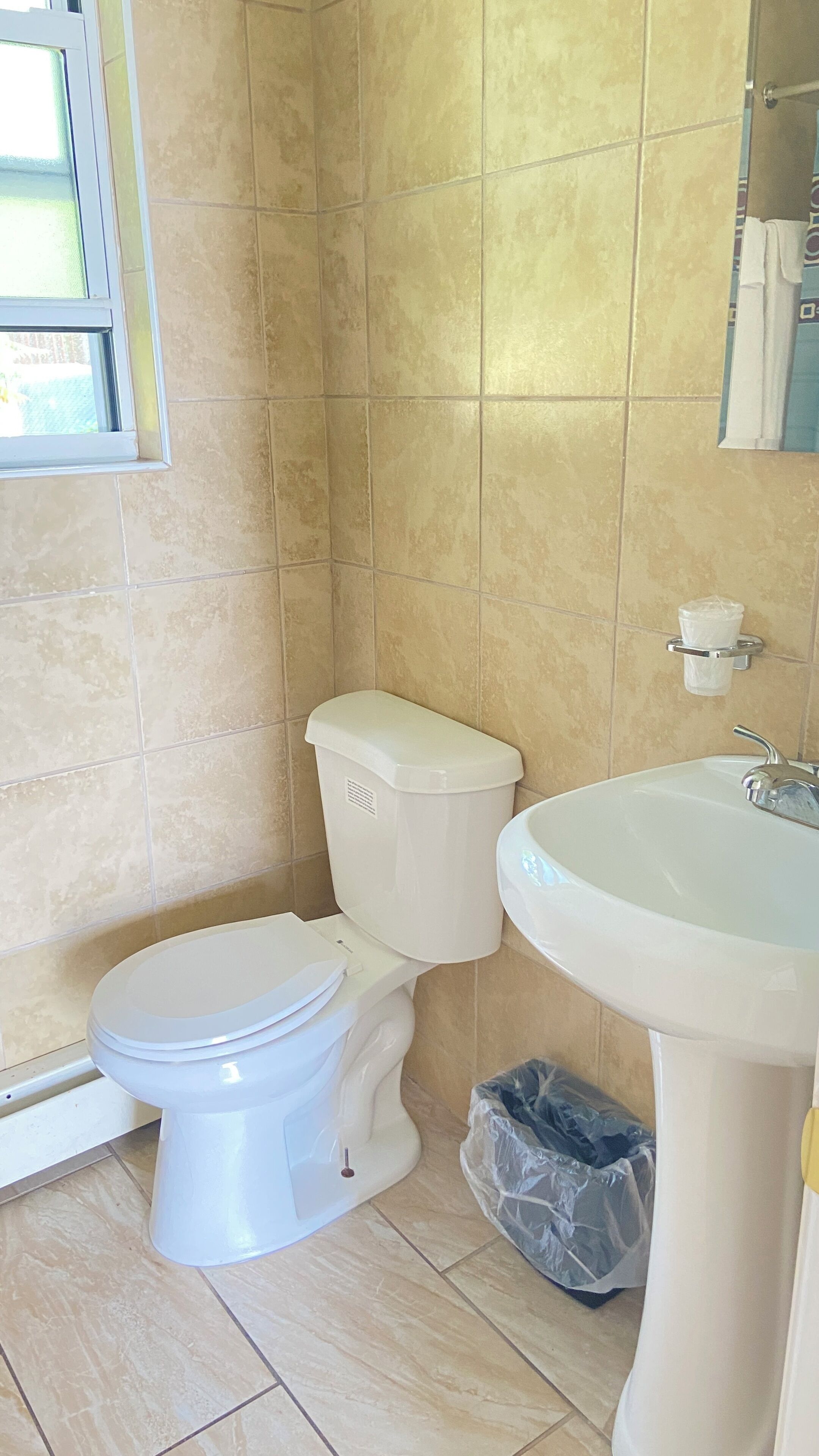 Une salle de bain avec des toilettes, un lavabo et des murs carrelés.