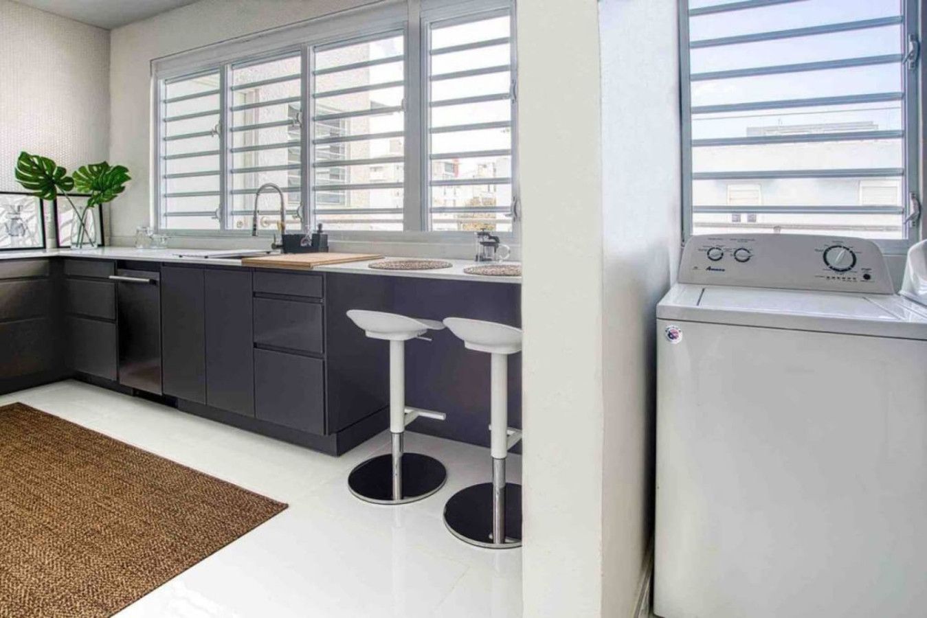 A modern kitchen with a large window, a sink, and a built-in washing machine.