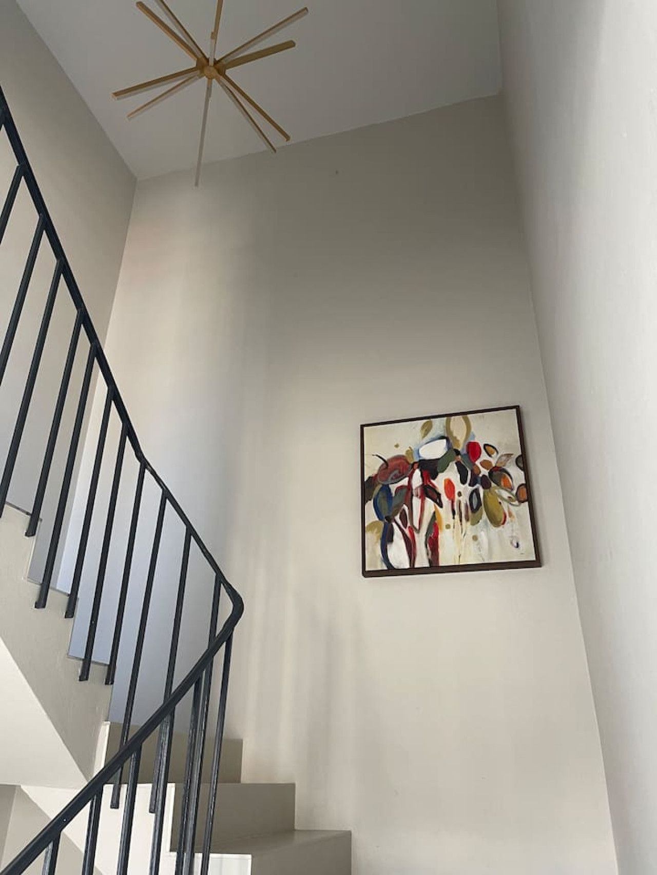 A staircase with a modern design, a ceiling fan, and a piece of abstract art on the wall.