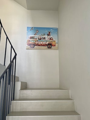 Una escalera con un cuadro colgado en la pared que muestra una camioneta con animales y la palabra 'teahouse'.