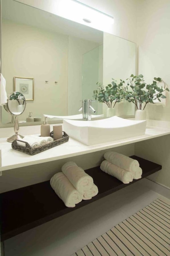 Un baño moderno con un espejo grande, un lavabo y un estante con toallas.