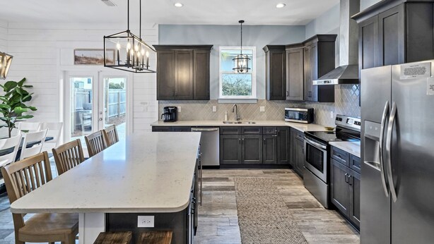 A modern kitchen with dark cabinets, stainless steel appliances, and a large island. -  Private Beach Access, Pool and Hot Tub! (Destin)
