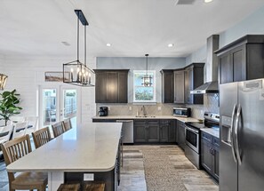 Una cocina moderna con armarios oscuros, electrodomésticos de acero inoxidable y una isla grande.