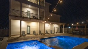 A two-story house with a swimming pool, outdoor seating, and string lights. -  Private Beach Access, Pool and Hot Tub! (Destin)