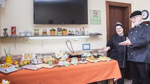 A buffet table with various food items and a television mounted on the wall. - Pousada Green House by Conrado Vitali (Canela)