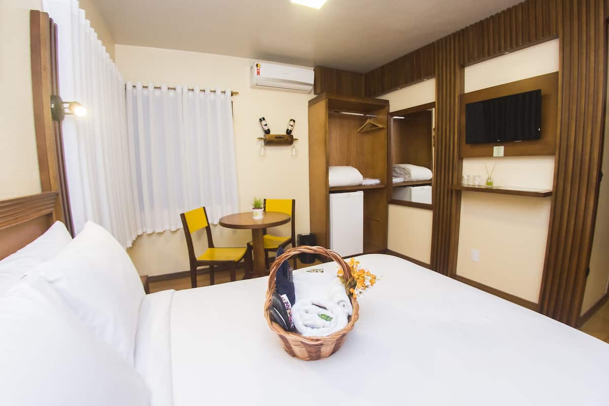 Ein Hotelzimmer mit einem Bett, einem kleinen Tisch mit Stuhl, einem Fernseher, einem Kleiderschrank und einer Reihe von Pflegeprodukten.