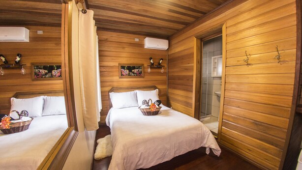 A wooden cabin room with two beds, a bathroom, and a small kitchenette. - Pousada Green House by Conrado Vitali (Canela)