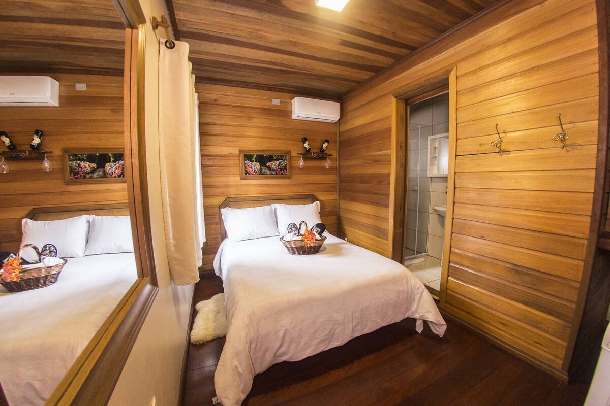 Ein Holzhütten-Zimmer mit zwei Betten, einem Badezimmer und einer kleinen Küchenzeile.