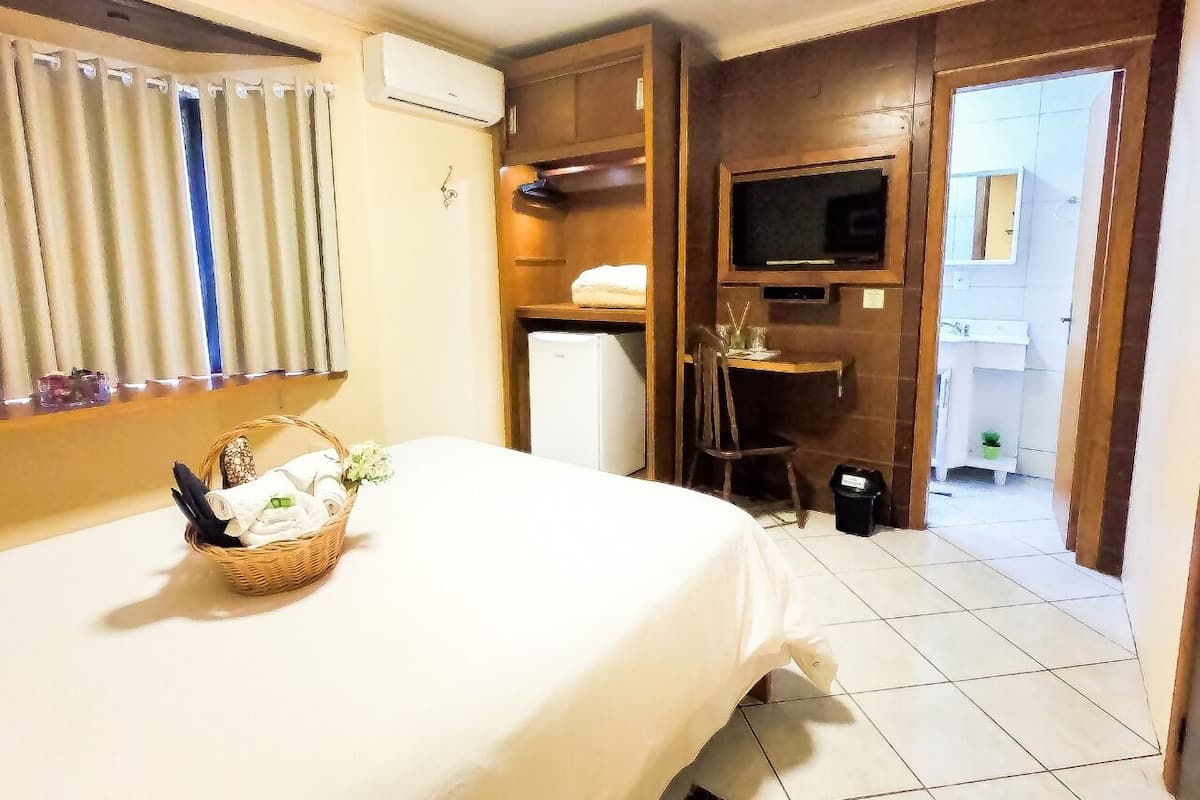 Ein Hotelzimmer mit einem Bett, einem kleinen Tisch mit einem Korb, einem Fernseher und einem Kühlschrank.