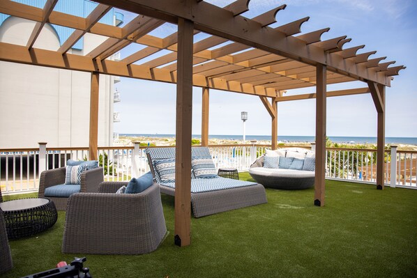 Un espacio de estar techado al aire libre con mobiliario de mimbre y vistas a la playa.