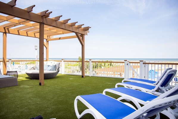 Un espacio al aire libre cubierto con césped artificial, sillas de lounge y una pérgola.
