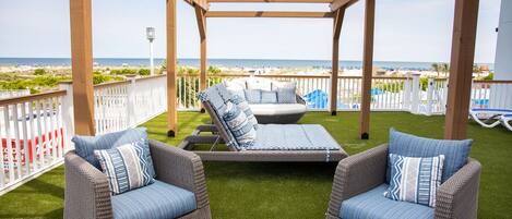 A covered outdoor seating area with wicker furniture and a view of the beach.