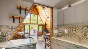 Una cocina con techo de madera, un comedor con mesa y sillas, y vistas al exterior.
