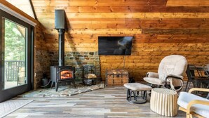 Un acogedor interior de cabaña con chimenea de piedra, paredes de madera y asientos cómodos.