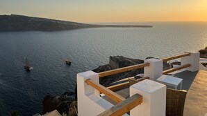 Ein Küstenblick mit einem hölzernen Balkon, der auf das Meer blickt, mit einer weißen Brüstung und einem kleinen Tisch.