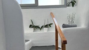 Eine Treppe mit weißen Stufen und einem Holnänder, die zu einer Zwischenebene mit einem Fenster und Pflanzen in Töpfen führt.