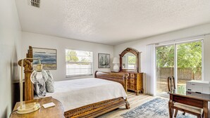 A bedroom with a large bed, wooden furniture, a desk, and a view of the outdoors. - 10 Mi to Dtwn Ocala: Dog-Friendly Home w/ Fire Pit (Ocala)