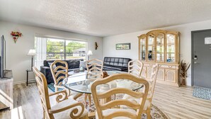 A spacious living room with a glass-top dining table surrounded by wooden chairs, a black leather sofa, and a wooden cabinet with glass doors. - 10 Mi to Dtwn Ocala: Dog-Friendly Home w/ Fire Pit (Ocala)