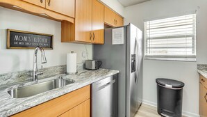 A kitchen with wooden cabinets, a stainless steel refrigerator, a sink, and a trash can. - 10 Mi to Dtwn Ocala: Dog-Friendly Home w/ Fire Pit (Ocala)