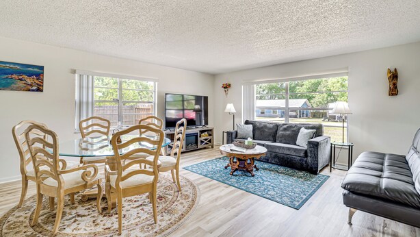 A living room with a glass-top dining table, wooden chairs, a sofa, a coffee table, and a TV. - 10 Mi to Dtwn Ocala: Dog-Friendly Home w/ Fire Pit (Ocala)