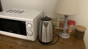 A microwave, a coffee maker, a lamp, and some food items on a wooden surface. - The Dimmer. 2 Bedroom Apartment (London)