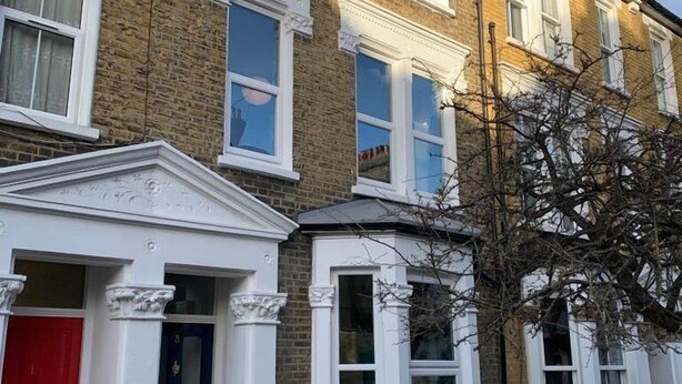 A row of terraced houses with white-framed windows and a red door. - The Dimmer. 2 Bedroom Apartment (London)