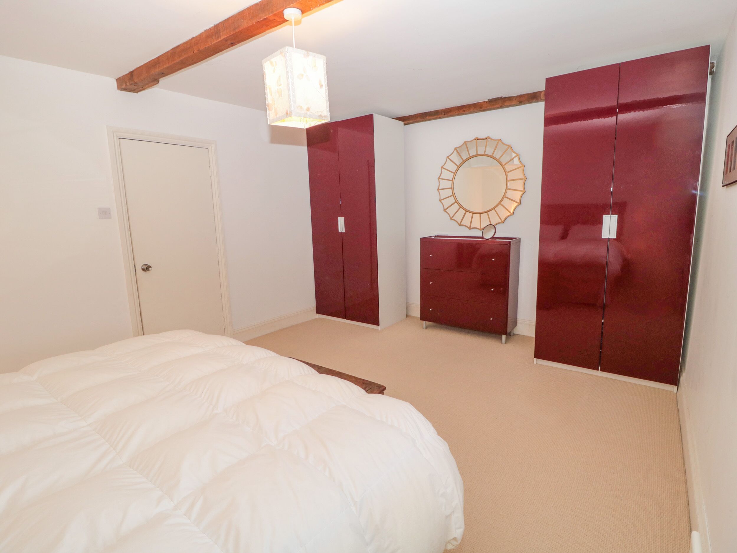A bedroom with a large bed, a wardrobe, a dresser, and a mirror on the wall.