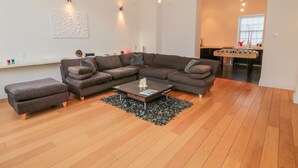 A modern living room with a sectional sofa, a coffee table, and a foosball table. - 2 The Reformed Church (Alnwick)