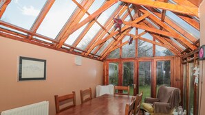 A conservatory with a wooden table and chairs, large windows, and a view of the garden. - 2 The Reformed Church (Alnwick)