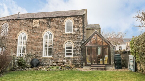 A stone building with arched windows and a conservatory. - 2 The Reformed Church (Alnwick)