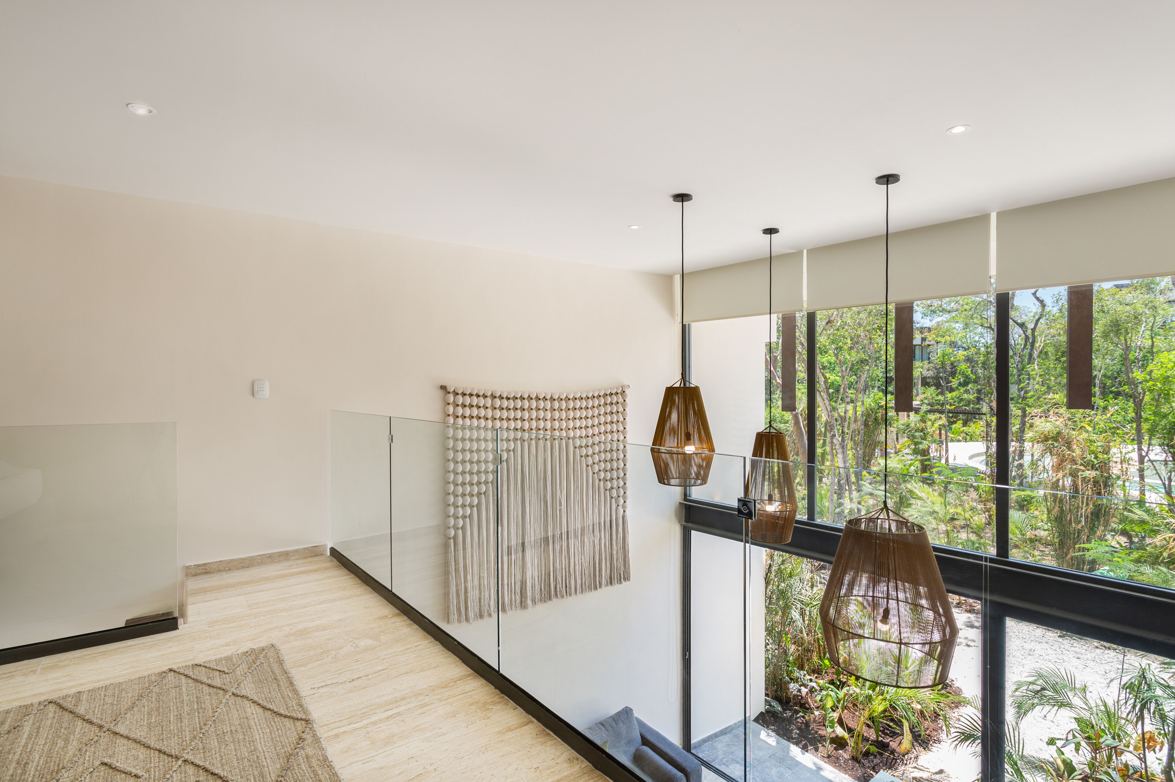 A modern room with a large window, a hanging light fixture, and a decorative wall hanging.