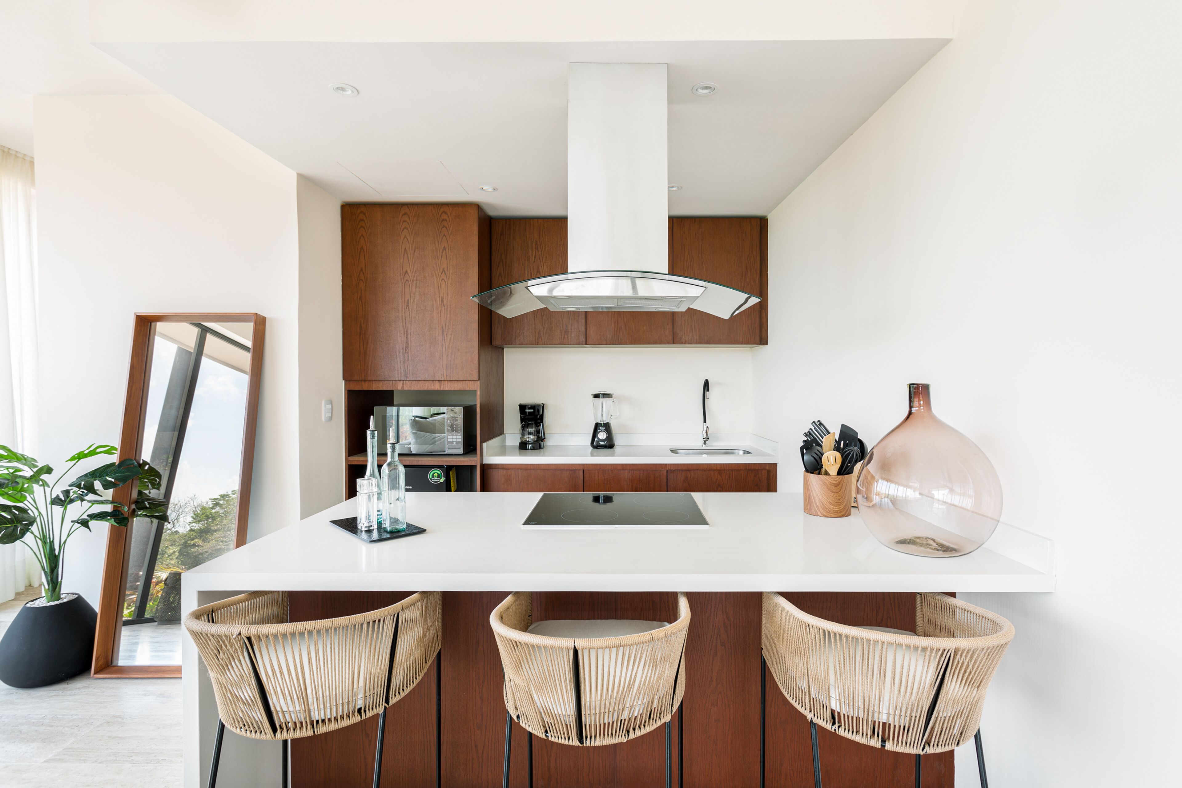 A modern kitchen with a large island, wooden cabinets, and a central range hood.