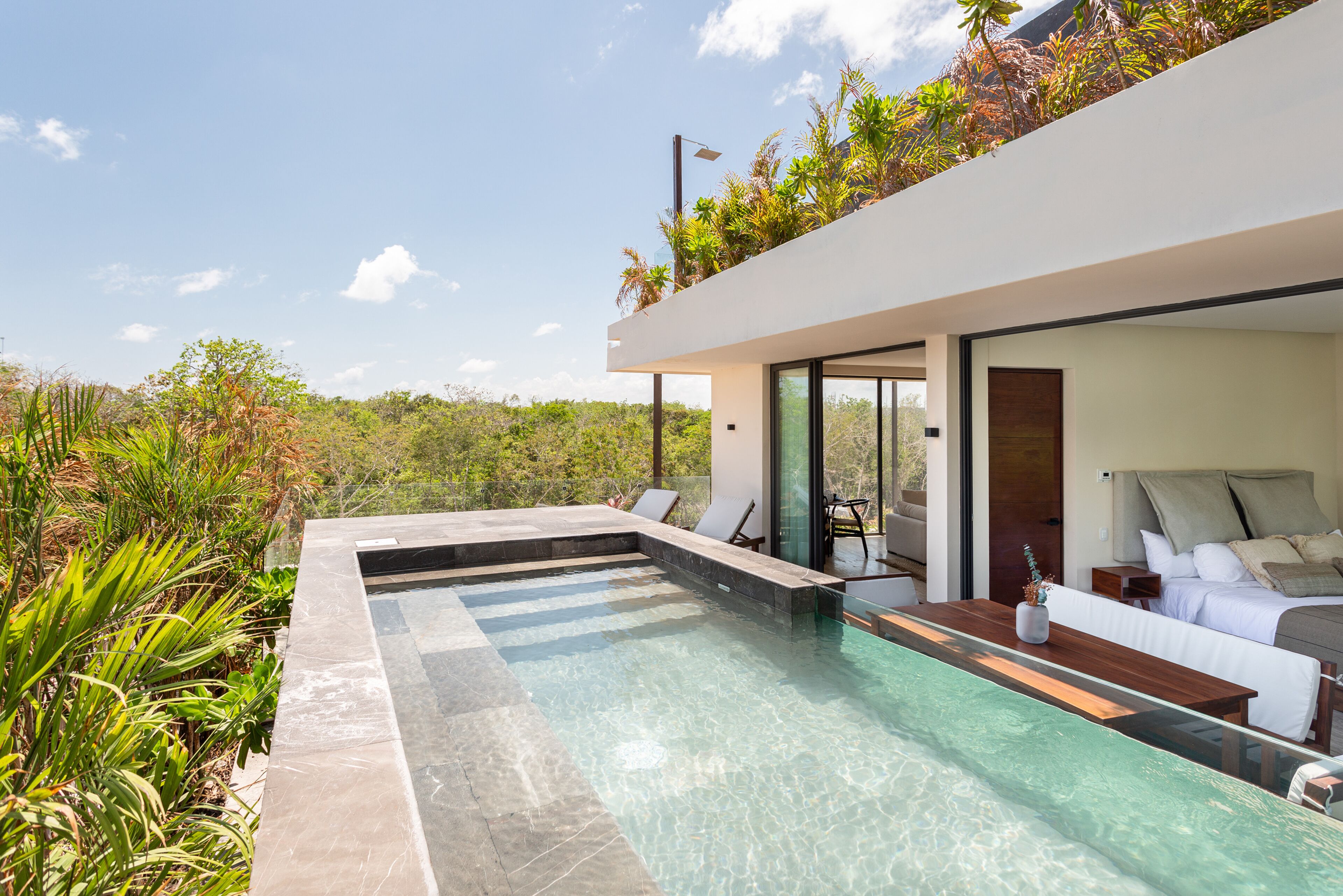Una casa moderna con piscina, un patio con posti a sedere e vista sul verde circostante.
