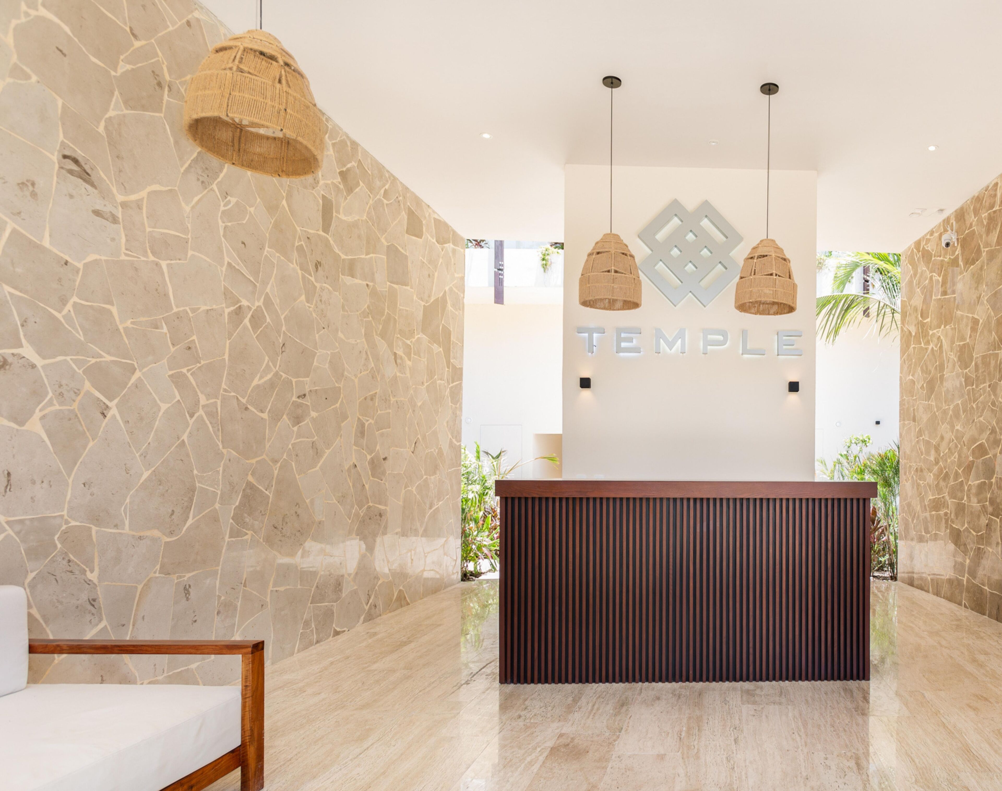 Una zona d'entrada amb una paret de pedra, un taulell de recepció i dues làmpades penjants.