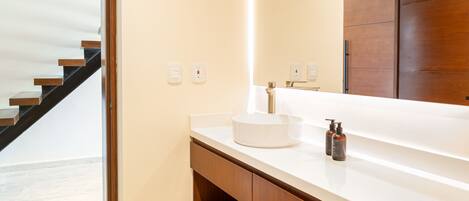 A modern bathroom with a white sink, wooden vanity, and a large mirror.