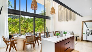 A modern dining area with a round table, wooden chairs, and hanging pendant lights. - Mistiq Temple I (Tulum)